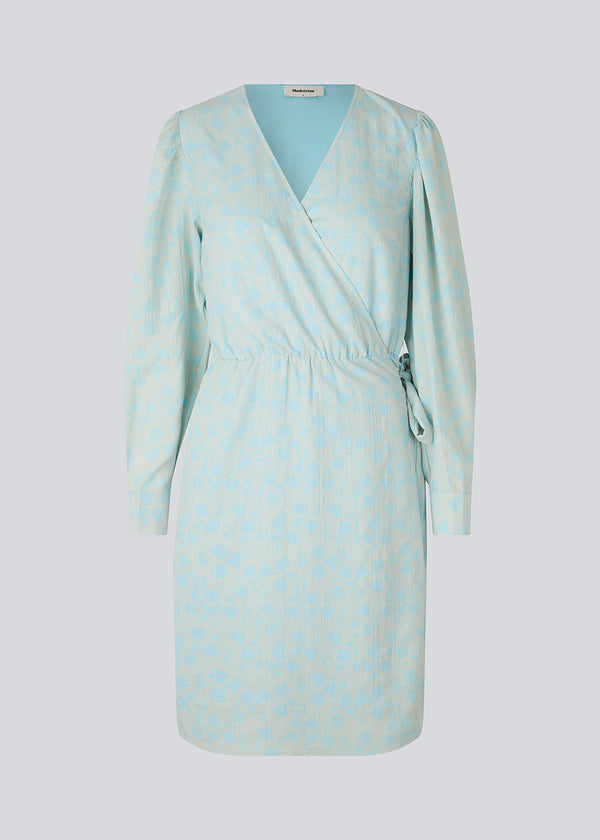Wrap dress in light blue with tiebelt at the waist, v-shaped neckline, and long puff sleeves. CupidMD print dress has a floral print.