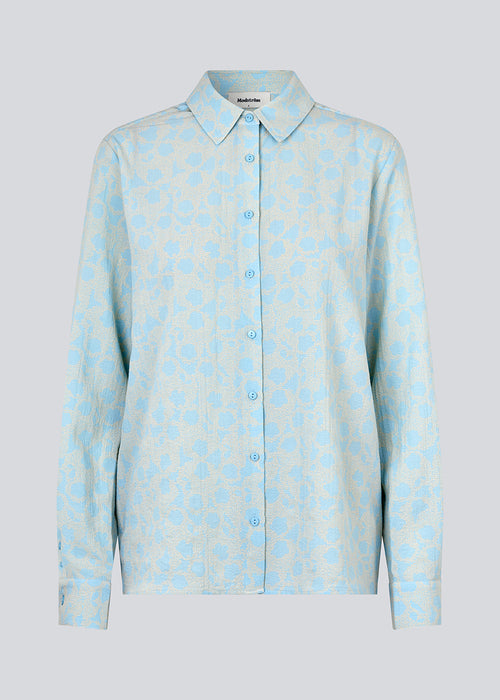 CupidMD print shirt in light blue is a shirt made of recycled polyester. It's a relaxed shirt with a pretty floral print.  The model is 177 cm and wears a size S/36.