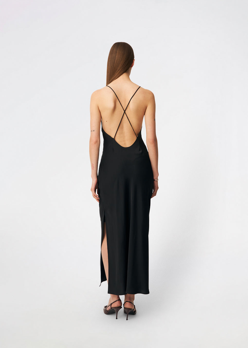 DanillaMD Dress is a long satin dress with an elegant, figure-hugging silhouette. The design features a straight neckline, thin straps and draped detailing at the side, creating a soft fall. The open back with delicate crossing straps adds a feminine touch. Style it with heels and simple accessories for special occasions. The model is 175 cm tall and is wearing a size S/36.
