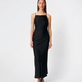 DanillaMD Dress is a long satin dress with an elegant, figure-hugging silhouette. The design features a straight neckline, thin straps and draped detailing at the side, creating a soft fall. The open back with delicate crossing straps adds a feminine touch. Style it with heels and simple accessories for special occasions. The model is 175 cm tall and is wearing a size S/36.