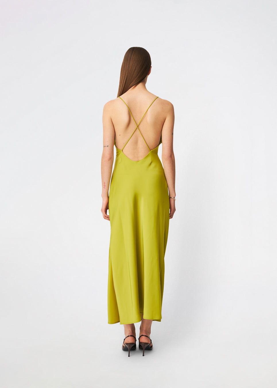 DanillaMD Dress is a long satin dress with an elegant, figure-hugging silhouette. The design features a straight neckline, thin straps and draped detailing at the side, creating a soft fall. The open back with delicate crossing straps adds a feminine touch. Style it with heels and simple accessories for special occasions. The model is 175 cm tall and is wearing a size S/36.
