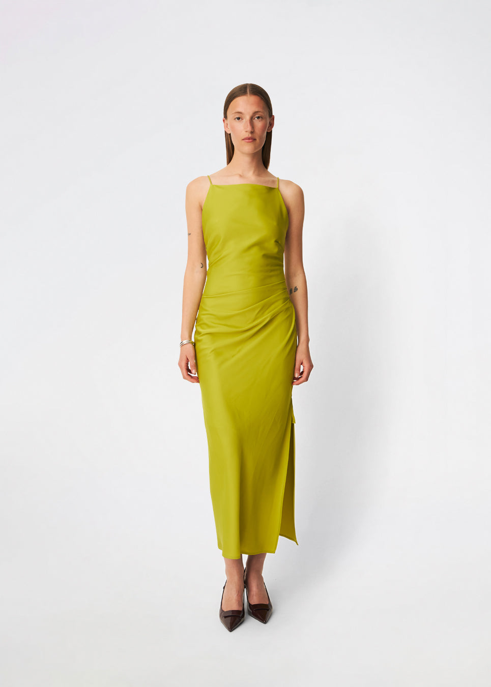 DanillaMD Dress is a long satin dress with an elegant, figure-hugging silhouette. The design features a straight neckline, thin straps and draped detailing at the side, creating a soft fall. The open back with delicate crossing straps adds a feminine touch. Style it with heels and simple accessories for special occasions. The model is 175 cm tall and is wearing a size S/36.