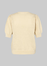 DariaMD o-neck is an open-knitted jumper in beige with short puff sleeves and a round neck. Ribbed trimmings at the bottom, neckline, and cuffs. The model is 177 cm and wears a size S/36.