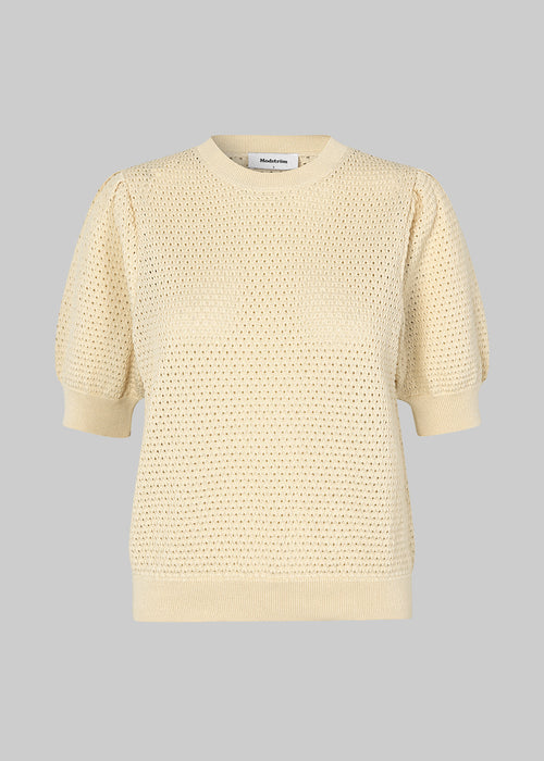 DariaMD o-neck is an open-knitted jumper in beige with short puff sleeves and a round neck. Ribbed trimmings at the bottom, neckline, and cuffs. The model is 177 cm and wears a size S/36.