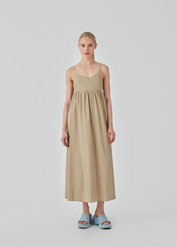 DarrelMD long dress in beige is designed in a linen mix with a figure-hugging top with a v-neckline, spaghetti straps with adjustable ties on the back, and a loose skirt. Lined. The model is 177 cm and wears a size S/36.