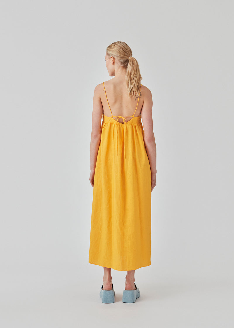 DarrelMD long dress in yellow is designed in a linen mix with a figure-hugging top with a v-neckline, spaghetti straps with adjustable ties on the back, and a loose skirt. Lined. The model is 177 cm and wears a size S/36.