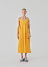 DarrelMD long dress in yellow is designed in a linen mix with a figure-hugging top with a v-neckline, spaghetti straps with adjustable ties on the back, and a loose skirt. Lined. The model is 177 cm and wears a size S/36.