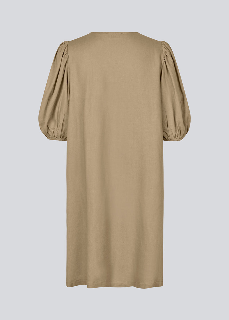 Mini dress in light brown with a loose fit and puff sleeves with elastic in the end. DarrelMD dress has an opening in the front with a button closure.