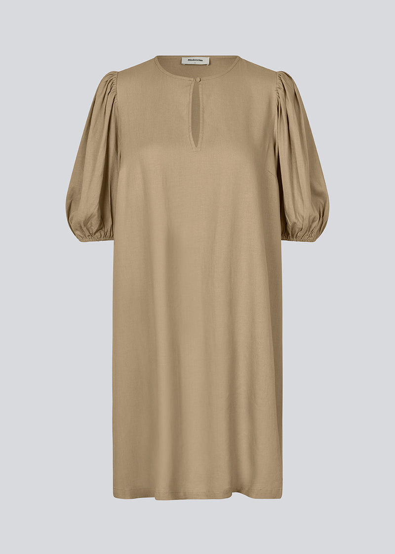 Mini dress in light brown with a loose fit and puff sleeves with elastic in the end. DarrelMD dress has an opening in the front with a button closure.