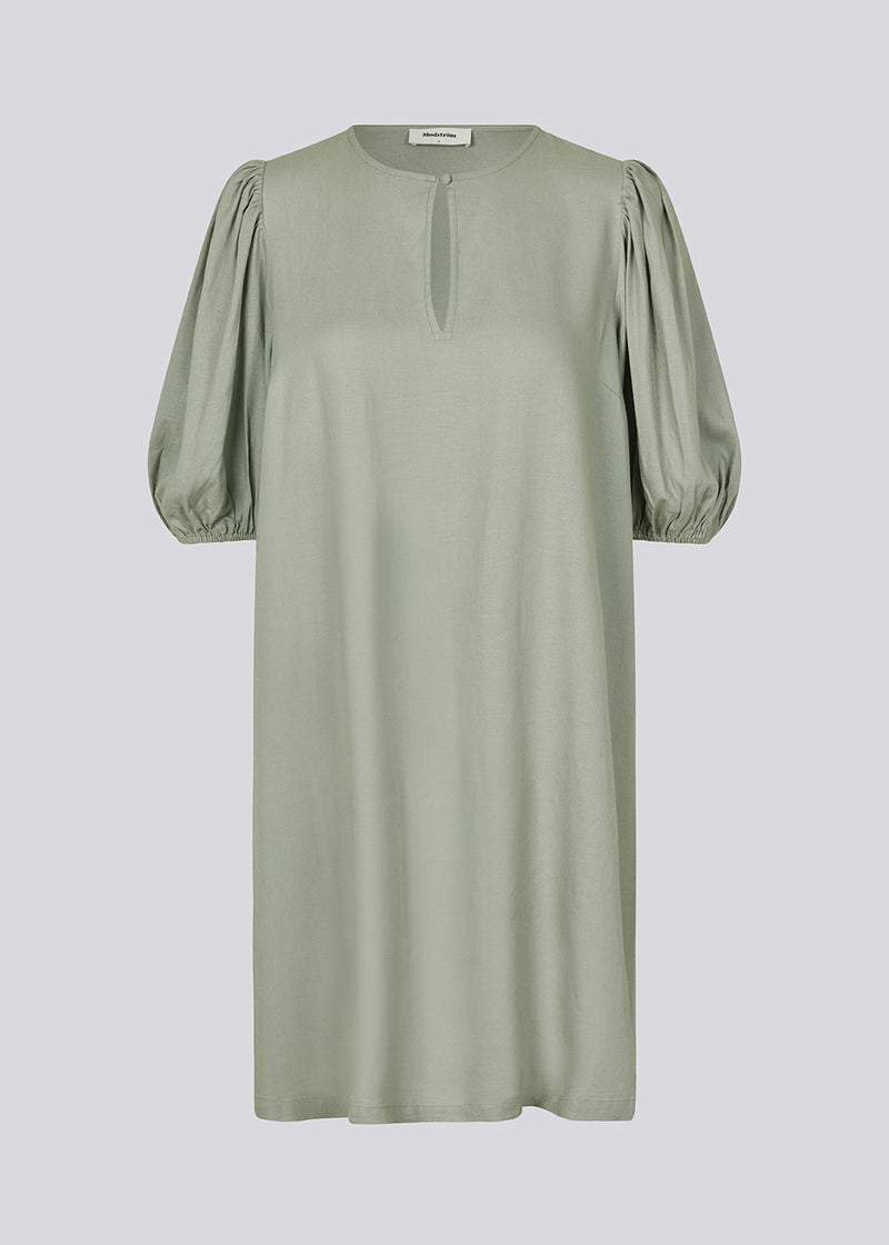 Mini dress in light green with a loose fit and puff sleeves with elastic in the end. DarrelMD dress has an opening in the front with a button closure.