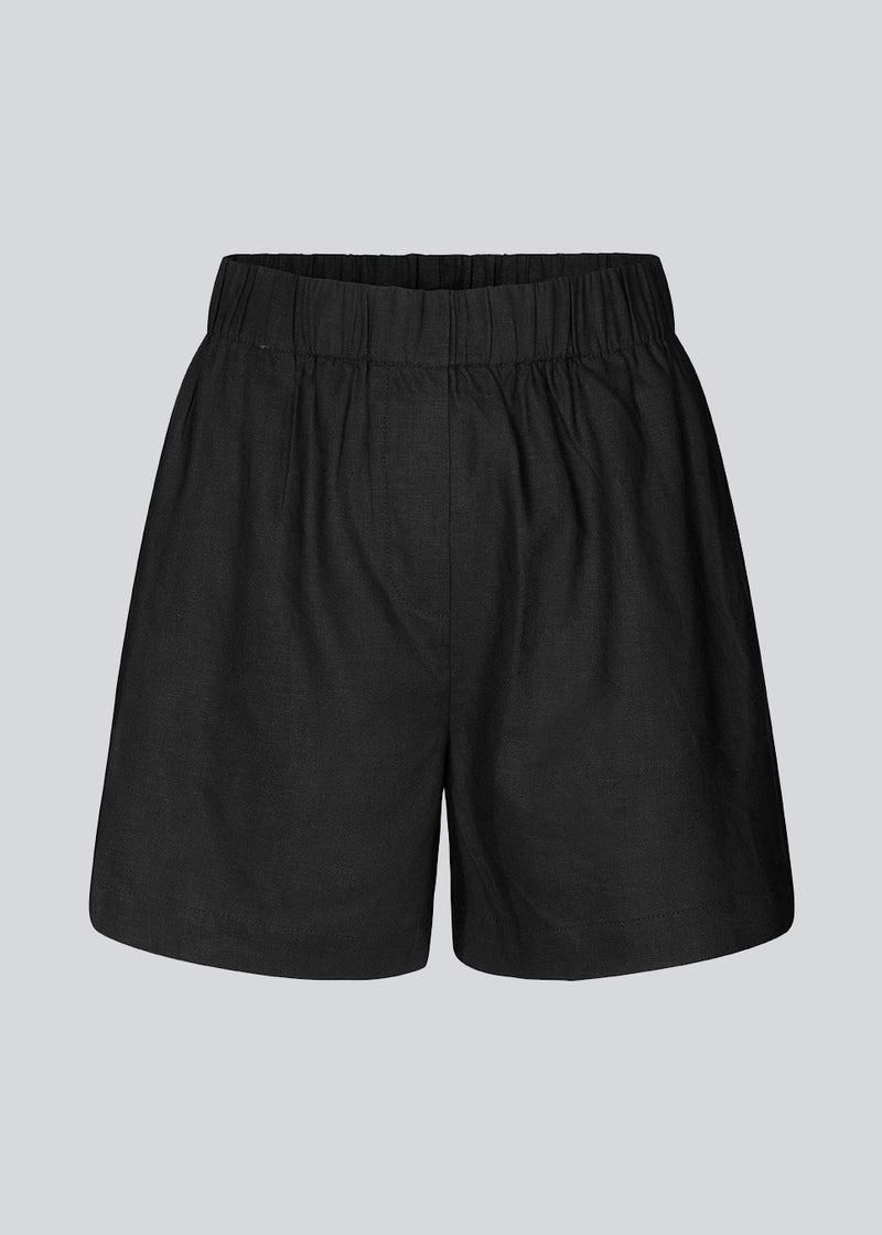 Shorts in black in a relaxed fit, wide legs, and an elasticated waistband. DarrelMD shorts are crafted from a linen material. The model is 177 cm and wears a size S/36.