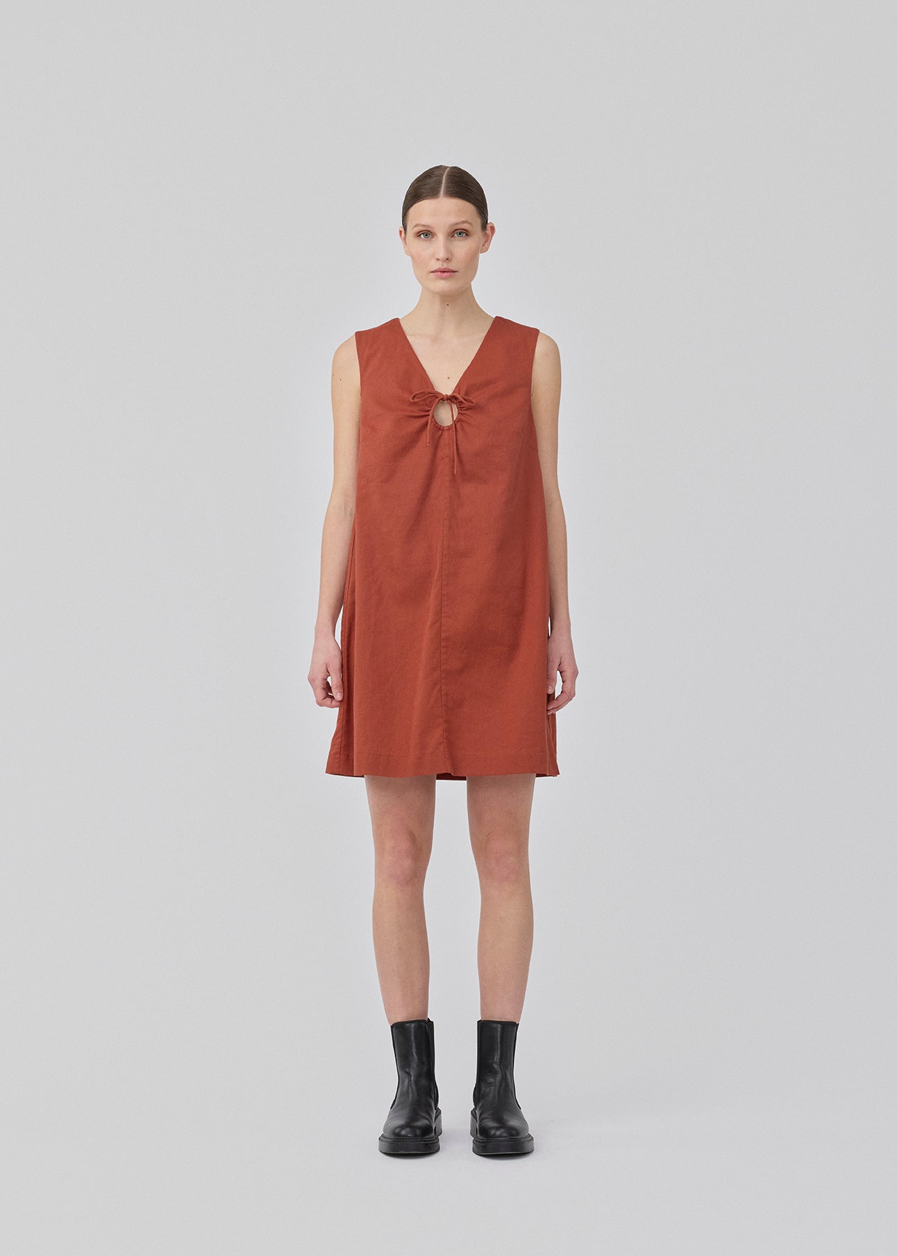 Short dark red dress in a linen blend with an A-line silhouette. DaynaMD dress is sleeveless, and features a deep v-neckline with cut-out details and ties. The model is 177 cm and wears a size S/36.
