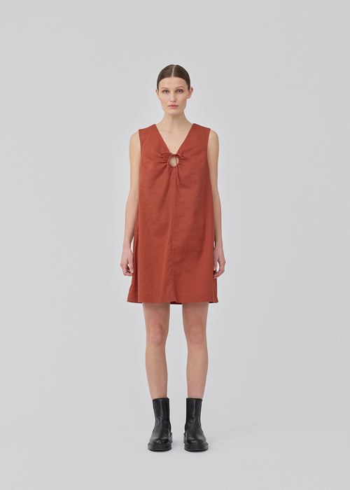 Short dark red dress in a linen blend with an A-line silhouette. DaynaMD dress is sleeveless, and features a deep v-neckline with cut-out details and ties. The model is 177 cm and wears a size S/36.