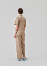 Jumpsuit in a crispy cotton blend with long, wide legs. DedeMD jumpsuit has short sleeves, collar, and zipper down the front. Belt straps at the waist. The model is 177 cm and wears a size S/36.