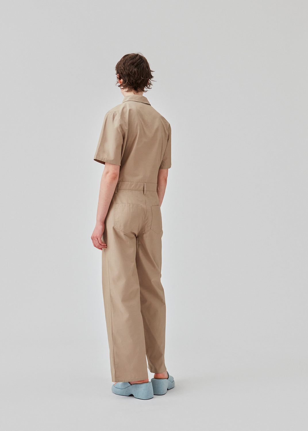 Jumpsuit in a crispy cotton blend with long, wide legs. DedeMD jumpsuit has short sleeves, collar, and zipper down the front. Belt straps at the waist. The model is 177 cm and wears a size S/36.