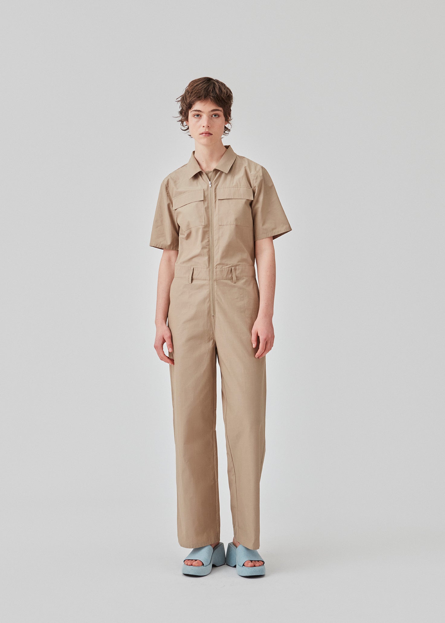 Jumpsuit in a crispy cotton blend with long, wide legs. DedeMD jumpsuit has short sleeves, collar, and zipper down the front. Belt straps at the waist. The model is 177 cm and wears a size S/36.