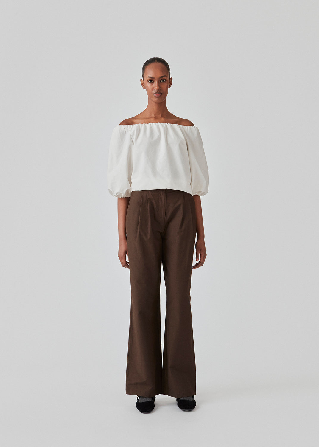 Suit pants in dark brown in a cotton blend with a relaxed silhouette and wide legs. DeenMD pants have a medium waist, zip fly, and pleats at the front. The model is 177 cm and wears a size S/36.