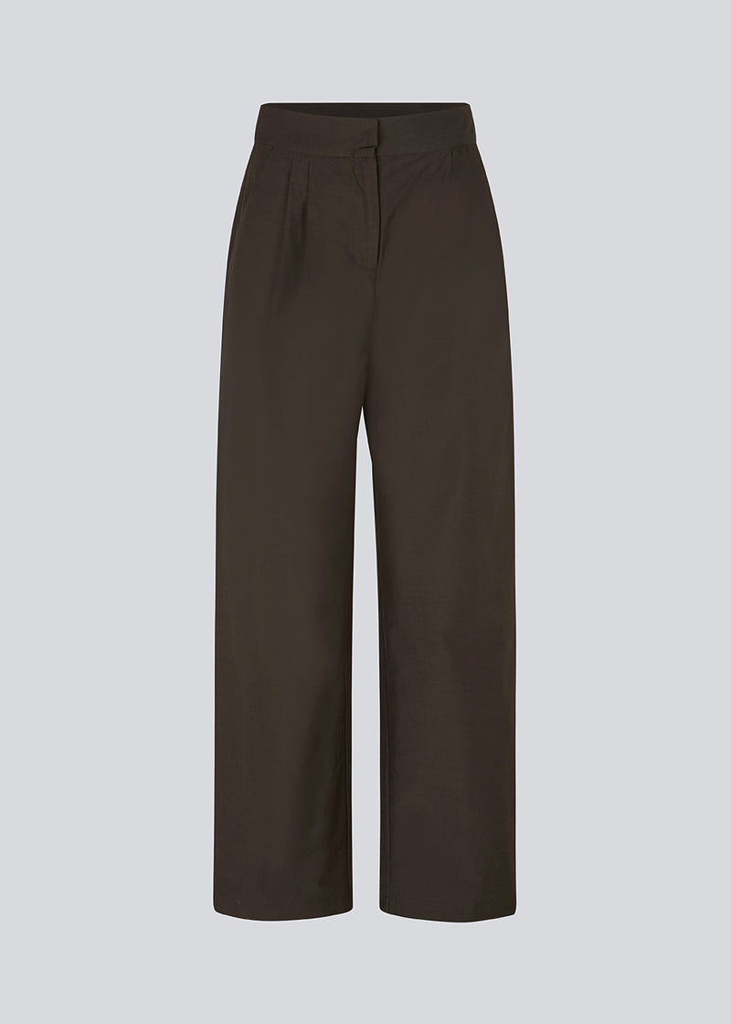 Suit pants in dark brown in a cotton blend with a relaxed silhouette and wide legs. DeenMD pants have a medium waist, zip fly, and pleats at the front. The model is 177 cm and wears a size S/36.