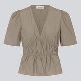 Beige top made from a cotton mix with short, slightly puffed, sleeves, and a deep v-neckline. DeenMD top has a flattering ruched detail below the chest and at the waist. The model is 177 cm and wears a size S/36.