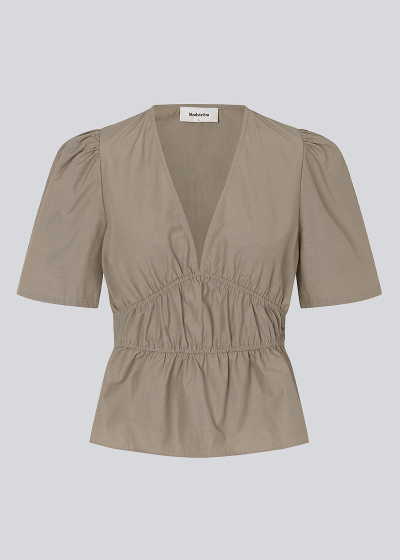 Beige top made from a cotton mix with short, slightly puffed, sleeves, and a deep v-neckline. DeenMD top has a flattering ruched detail below the chest and at the waist. The model is 177 cm and wears a size S/36.