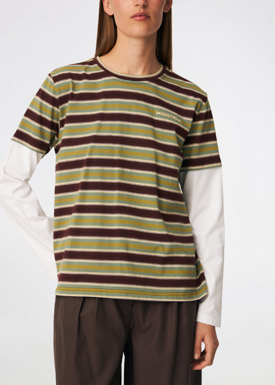 The Denismd Contrast Tee is a layered-look T-shirt combining a striped rib fabric with contrasting long sleeves for a relaxed, modern aesthetic. Designed with a loose fit, classic crew neckline, and an embroidered Modström logo at the chest for a sporty finish. Pair it with jeans, cargo trousers, or tailored pants for an effortless everyday look.