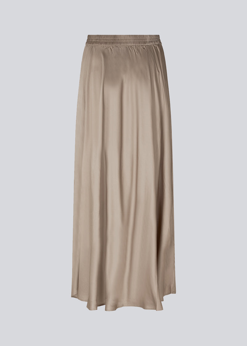 Long beige skirt with wide skirt. DevanMD skirt is designed in a shiny satin material with elasticated medium waist. The model is 177 cm and wears a size S/36.