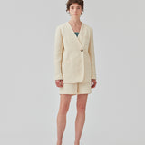 DimeMD blazer is designed in a textured cotton blend with lining. The blazer is collarless but has an asymmetrical wrap detail with a single visible button. The model is 177 cm and wears a size S/36.  Style the blazer with matching shorts: DimeMD shorts.