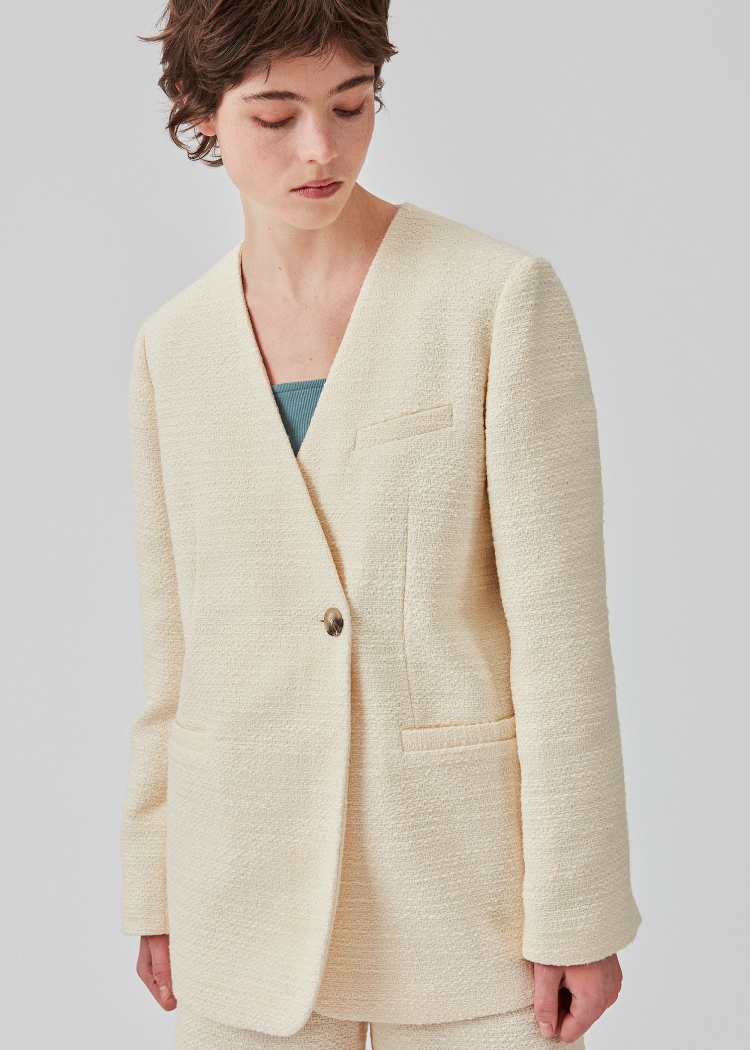 DimeMD blazer is designed in a textured cotton blend with lining. The blazer is collarless but has an asymmetrical wrap detail with a single visible button. The model is 177 cm and wears a size S/36.  Style the blazer with matching shorts: DimeMD shorts.