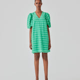 Short dress in green in a seersucker material. DinoMD dress has a v-shaped neckline, a loose silhouette, and short puff sleeves with elastic. The model is 177 cm and wears a size S/36.