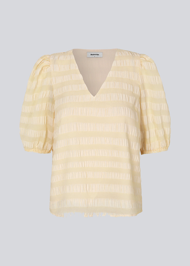 DinoMD top in beige is designed in a seersucker material with a relaxed fit. The top has a v-neckline and short puff sleeves with elasticated cuffs. 