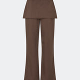 The Dodomd Pants feature a straight-leg silhouette with an integrated skirt overlay that creates a modern, statement look. A slim waist strap with a metal buckle adds a refined finishing touch, while the clean tailoring makes them easy to style. Pair them with the matching Dodomd Top or a simple knit for an elevated everyday outfit.