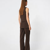 The Dodomd Top is an elegant sleeveless top with a clean, tailored silhouette. The high neckline with decorative press buttons and concealed front closure create a modern, minimalist look, while the shaping seams enhance the fit. Wear it on its own or style it with the matching trousers for a refined coordinated outfit.
