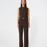 The Dodomd Top is an elegant sleeveless top with a clean, tailored silhouette. The high neckline with decorative press buttons and concealed front closure create a modern, minimalist look, while the shaping seams enhance the fit. Wear it on its own or style it with the matching trousers for a refined coordinated outfit.
