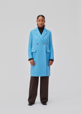 Double-breasted coat with lapels and buttons in front. EdinMD coat has a midi length with long sleeves, front pockets with a flap and single back vent. Lined. The model is 175 cm and wears a size S/36.