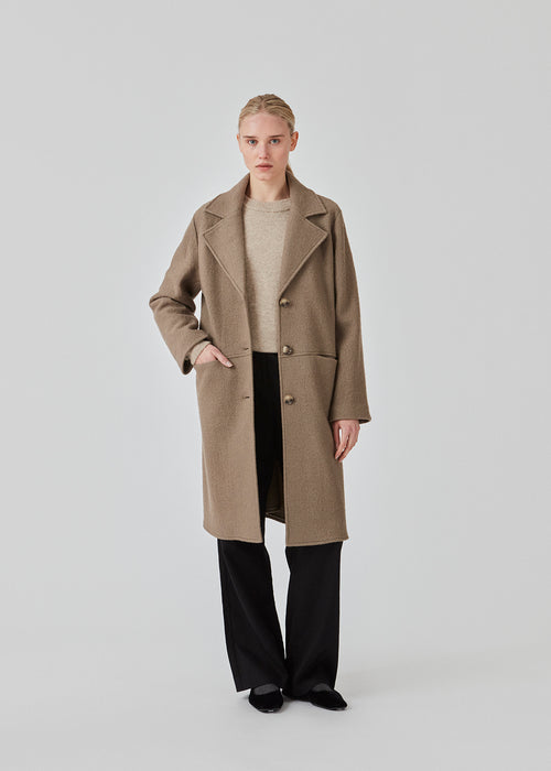 Lighter woolen coat with an overzied look and a wide collar with lapel. EilishMD coat is detailed with large buttons in front and two hidden pockets. The model is 175 cm and wears a size S/36.