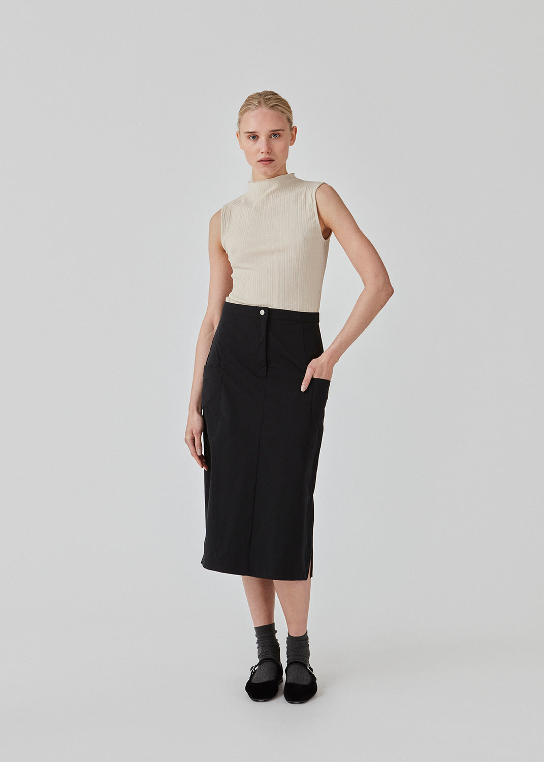 Midi skirt in black in a crisp woven quality. EmeryMD skirt has two patch pockets and a slit at each side. The model is 175 cm and wears a size S/36.