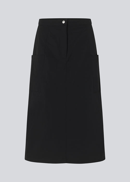 Midi skirt in black in a crisp woven quality. EmeryMD skirt has two patch pockets and a slit at each side. The model is 175 cm and wears a size S/36.