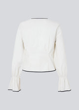 Fitted top in white with long loose sleeves. EmiliaMD shirt is closed with tree black tie bands in front and has a ruffle detail at the sleeve.