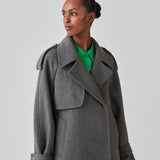 Cropped double-breasted wool coat with hidden buttons. EsmundMD jacket, in the colot Dark Grey Melange, has classic coat details with raglan sleeves and an high yoke at the back. Lined. The model is 175 cm and wears a size S/36.