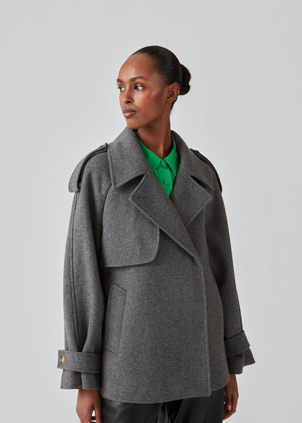 Cropped double-breasted wool coat with hidden buttons. EsmundMD jacket, in the colot Dark Grey Melange, has classic coat details with raglan sleeves and an high yoke at the back. Lined. The model is 175 cm and wears a size S/36.