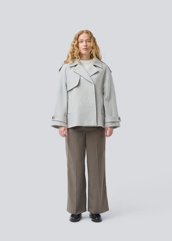 Cropped double-breasted wool coat in light grey with hidden buttons. EsmundMD jacket has classic coat details with raglan sleeves and an high yoke at the back. Lined. The model is 175 cm and wears a size S/36.