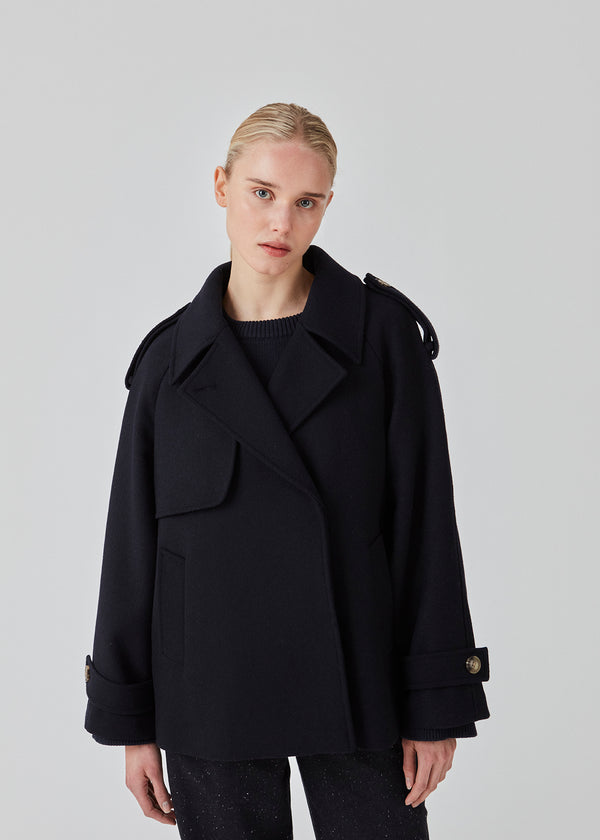 Cropped double-breasted wool coat with hidden buttons. EsmundMD jacket, in the colot Navy Sky, has classic coat details with raglan sleeves and an high yoke at the back. Lined. The model is 175 cm and wears a size S/36.