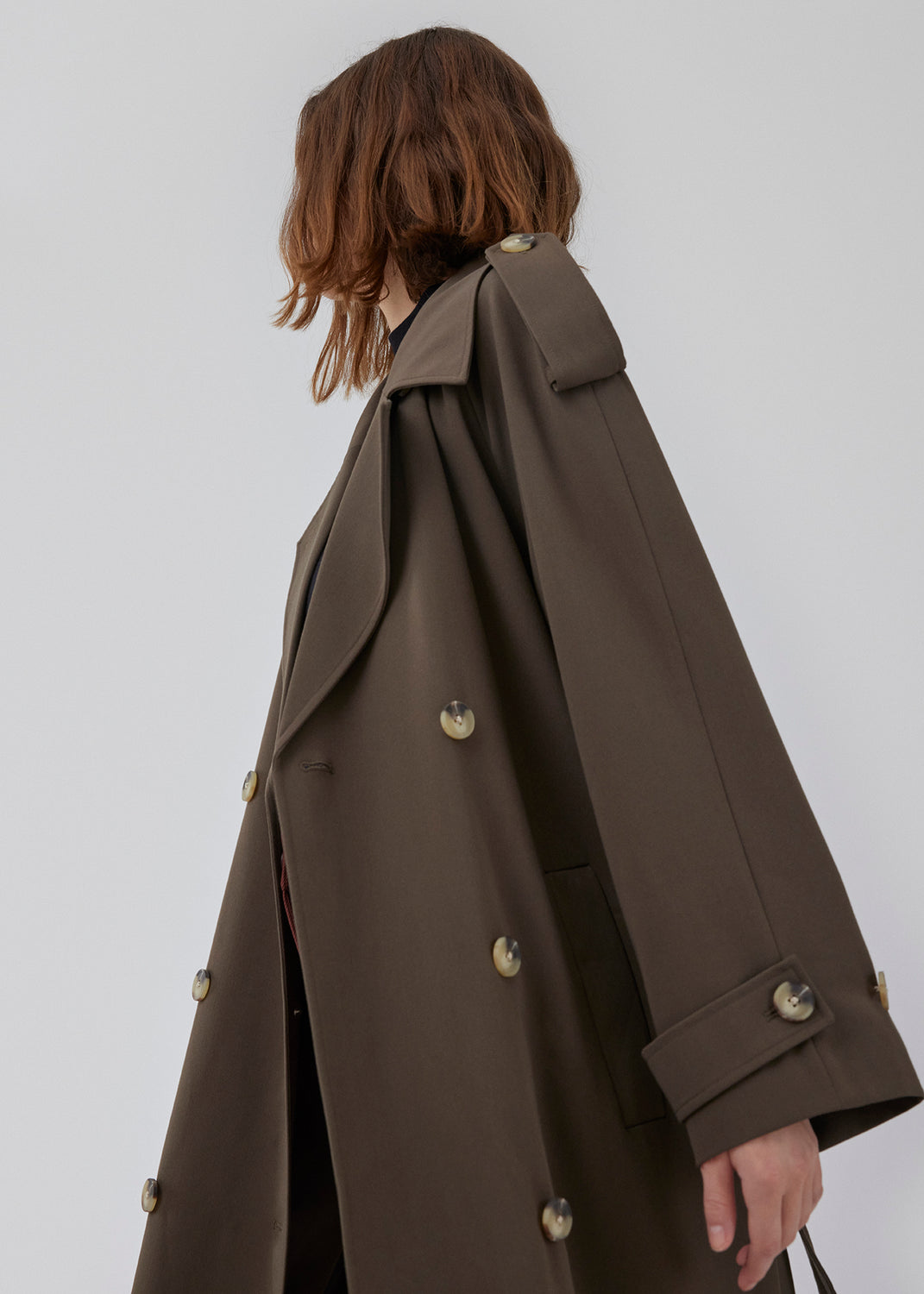 Oversized double-breasted trench coat in dark brown with tie belt at the waist. EvieMD jacket has dropped shoulders and long, wide sleeves. Lined