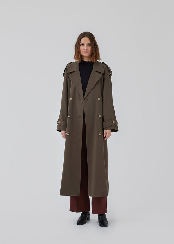 Oversized double-breasted trench coat in dark brown with tie belt at the waist. EvieMD jacket has dropped shoulders and long, wide sleeves. Lined