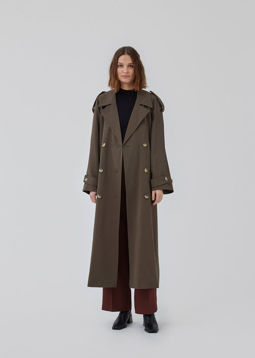 Oversized double-breasted trench coat in dark brown with tie belt at the waist. EvieMD jacket has dropped shoulders and long, wide sleeves. Lined