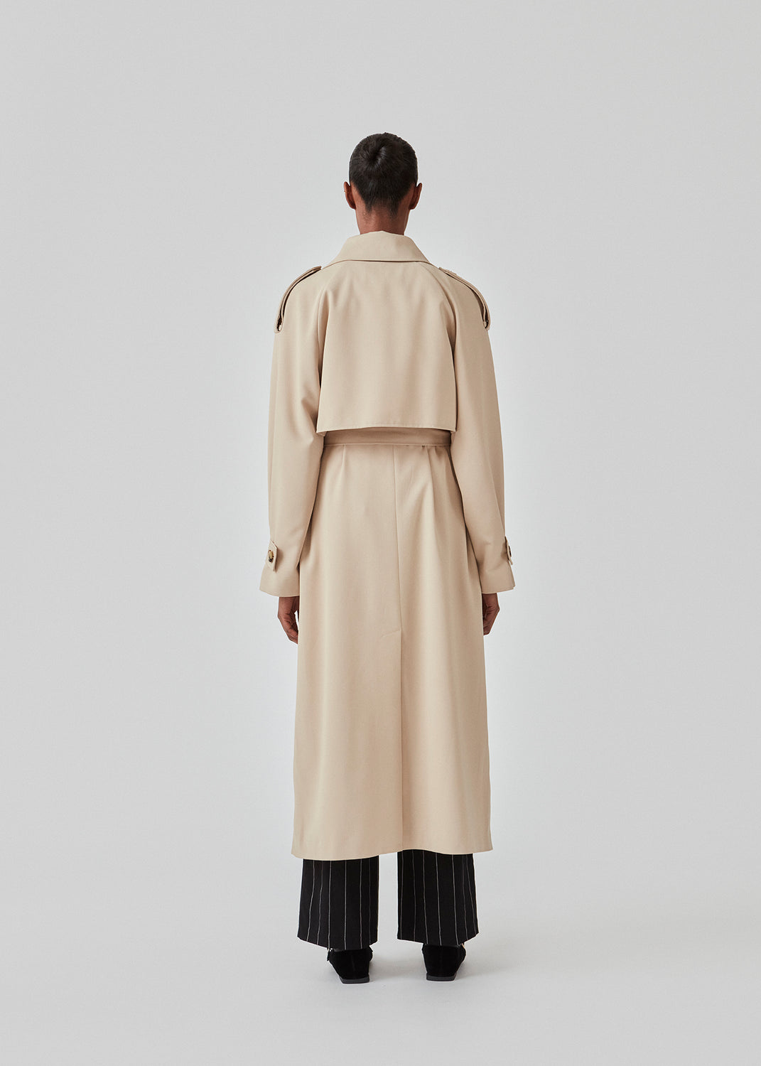 Oversized double-breasted trench coat in light beige with tie belt at the waist. EvieMD jacket has dropped shoulders and long, wide sleeves. Lined. The model is 175 cm and wears a size S/36.