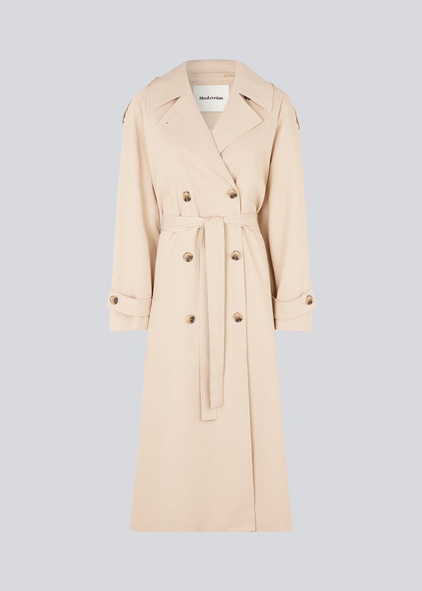 Oversized double-breasted trench coat in light beige with tie belt at the waist. EvieMD jacket has dropped shoulders and long, wide sleeves. Lined. The model is 175 cm and wears a size S/36.