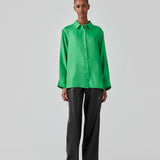 Green shirt in a silk quality with a loose shape. FableMD shirt has a collar and button closure in front, long voluminous sleeves and a wide cuff. The model is 175 cm and wears a size S/36.