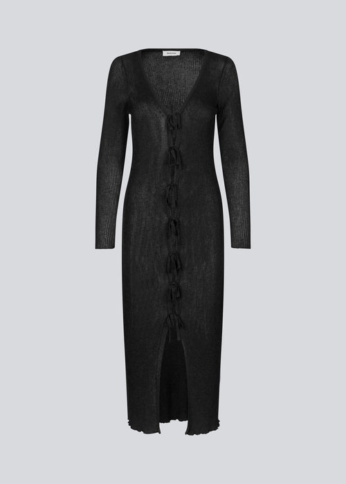 Long black dress in an airy knit with a slightly see-through design. FaddieMD dress has a v-neckline, long sleeves and tie band closure in front. 