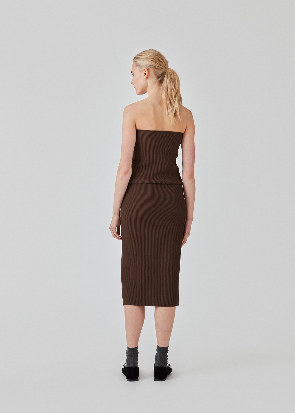 Tight fitted midi skirt in a soft, ribbed material. FainaMD skirt is designed with a high waist with covered elastication, and a high slit in front. Part of matching set. Buy the tube top here. The model is 175 cm and wears a siz